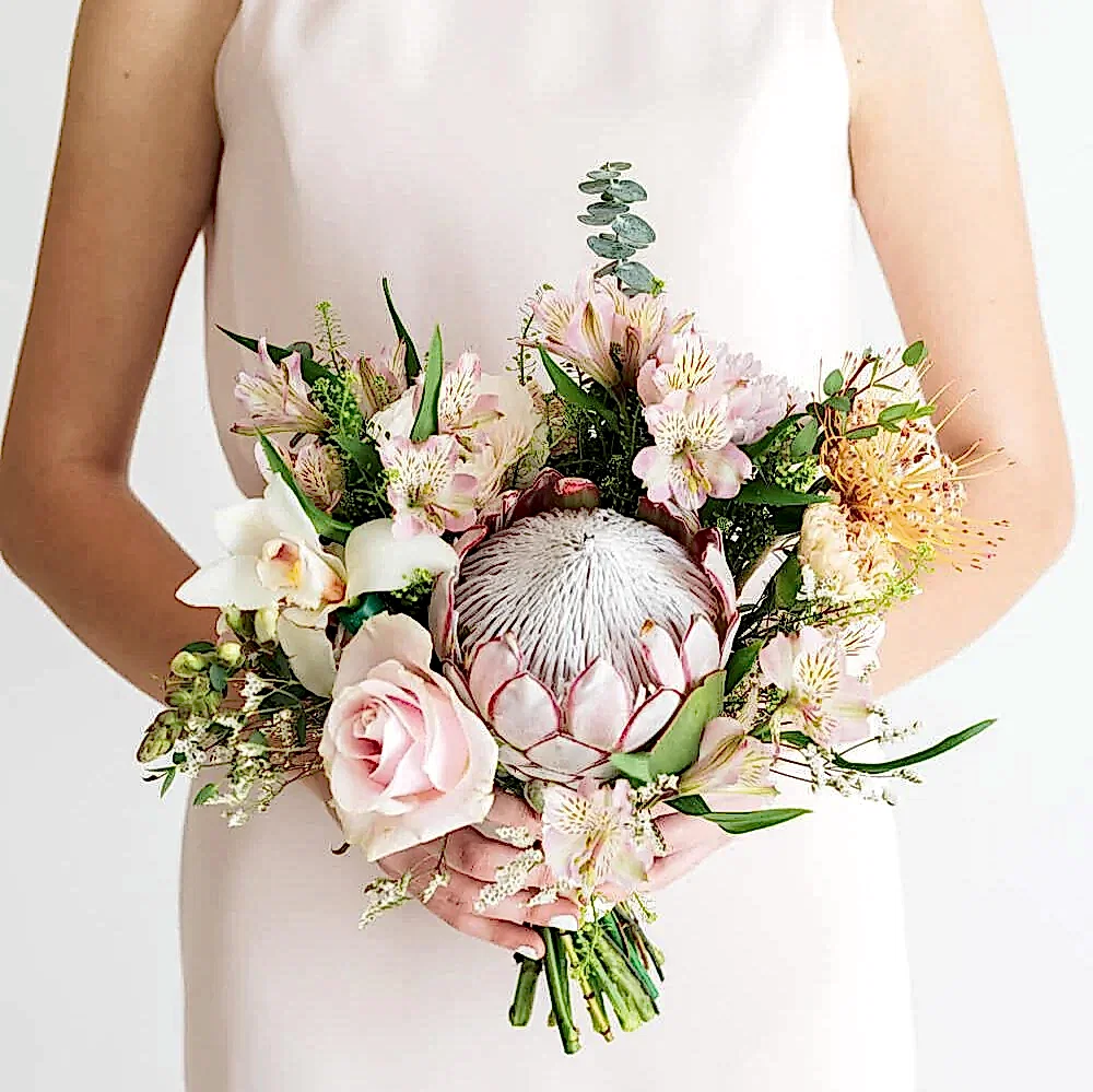 Woman in bridal attire displaying a romantic bouquet of flowers